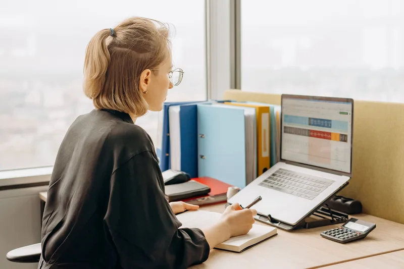 Virtual assistant reviewing a spreadsheet on her laptop while working from a home office
