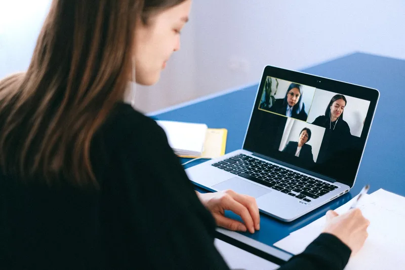 A candidate taking notes during a video call interview for a remote job