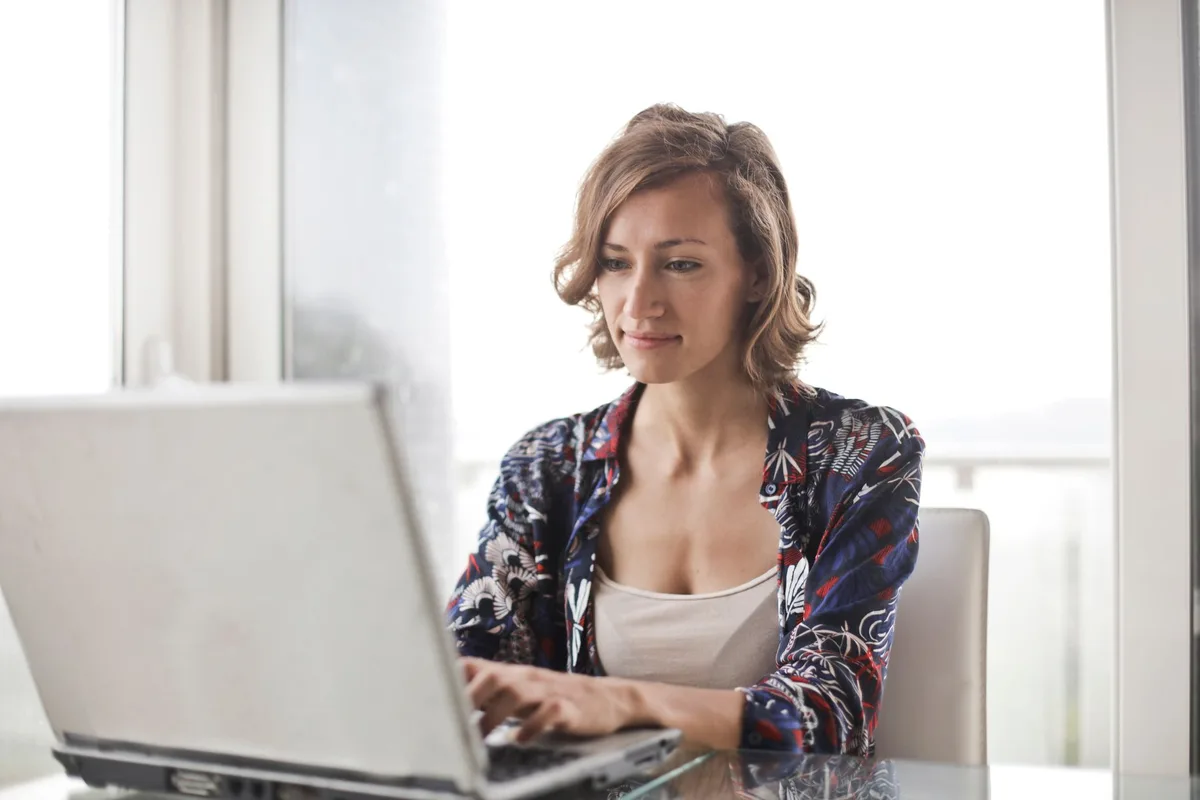 Remote worker typing on a laptop in a bright home office, searching for Amazon virtual assistant job listings