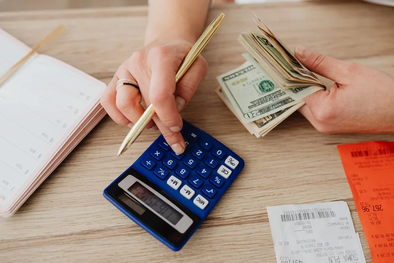 Calculator and cash used to budget monthly hiring costs