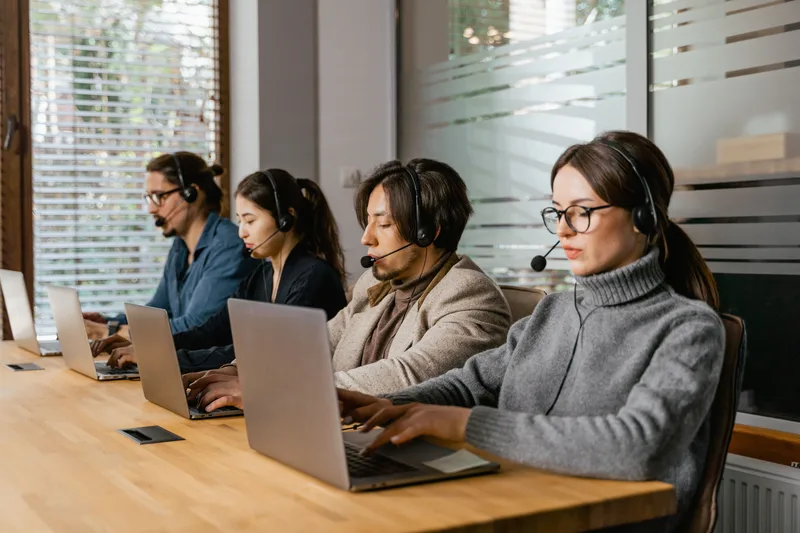 Customer service team handling buyer messages on laptops with headsets