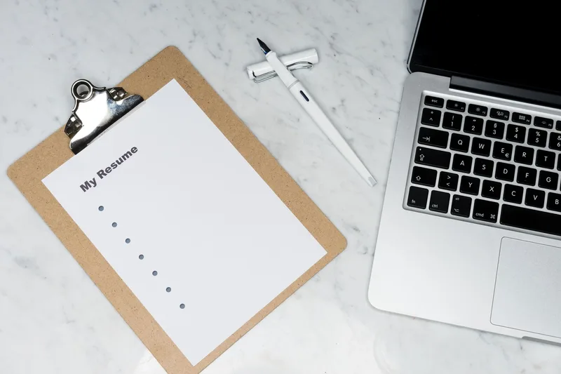 A one-page resume on a clipboard beside a laptop, representing simple, optional application materials for a VA job