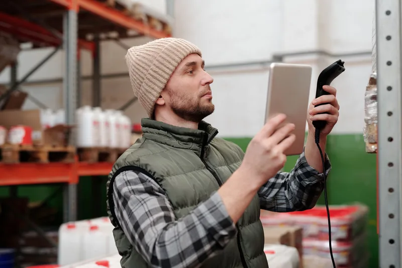 Warehouse worker using a scanner to check inventory, representing stock tracking work an ecommerce VA performs