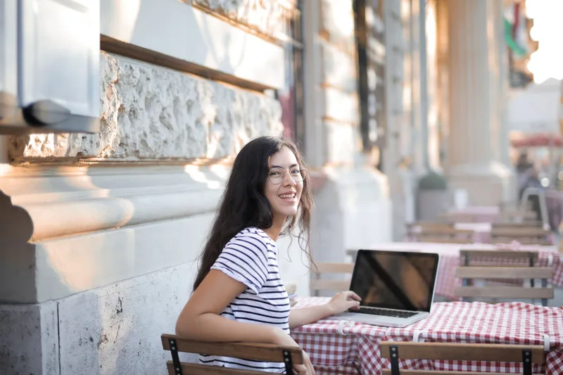 Smiling virtual assistant using a laptop outdoors
