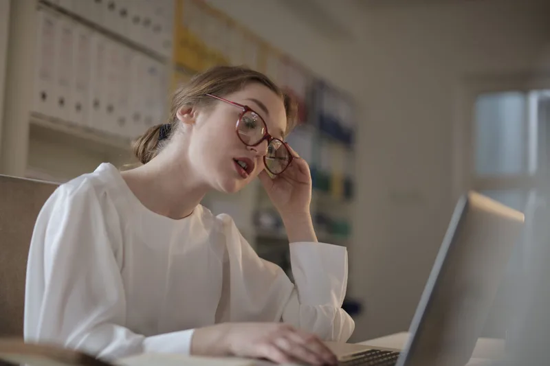 Woman working carefully at her laptop reviewing messages in a home office