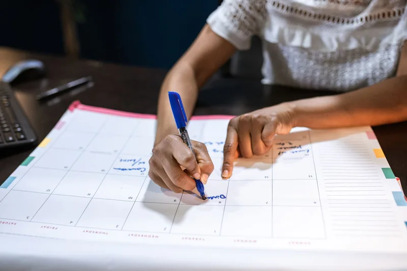 Person marking calendar planning VA job search schedule around existing commitments