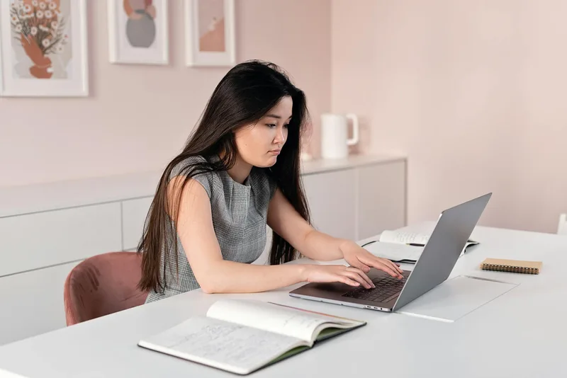 Filipino VA organized at home workspace reviewing job listings on a laptop with a notebook open beside them