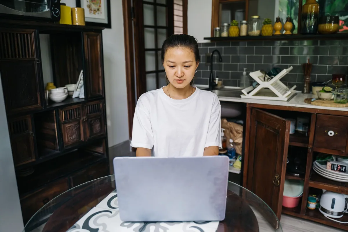 Filipino virtual assistant working from home on a laptop at the kitchen table