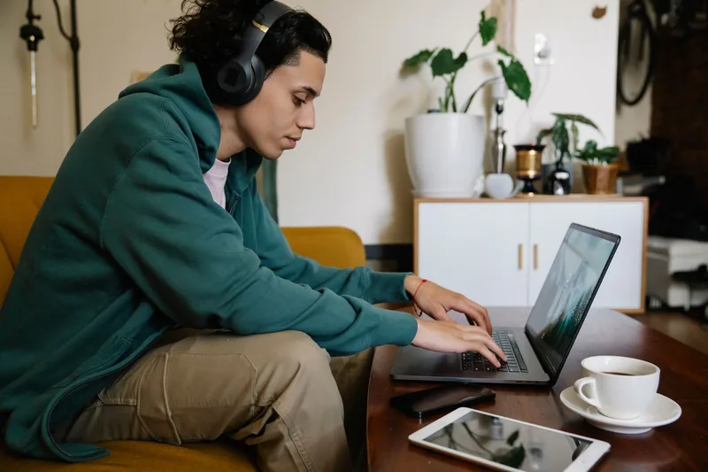Remote worker wearing a headset and typing on a laptop, demonstrating clear communication habits