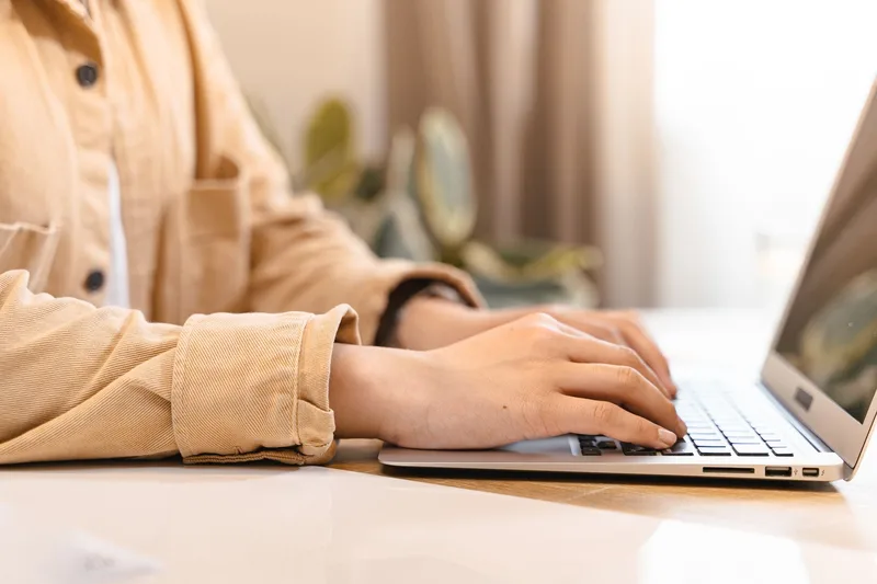 Young professional typing on a laptop while building an online work profile