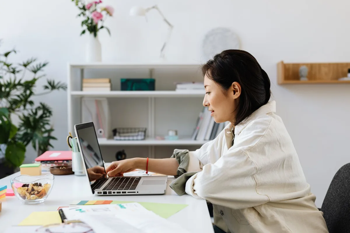Filipino woman working from home on a laptop with a plant on her desk