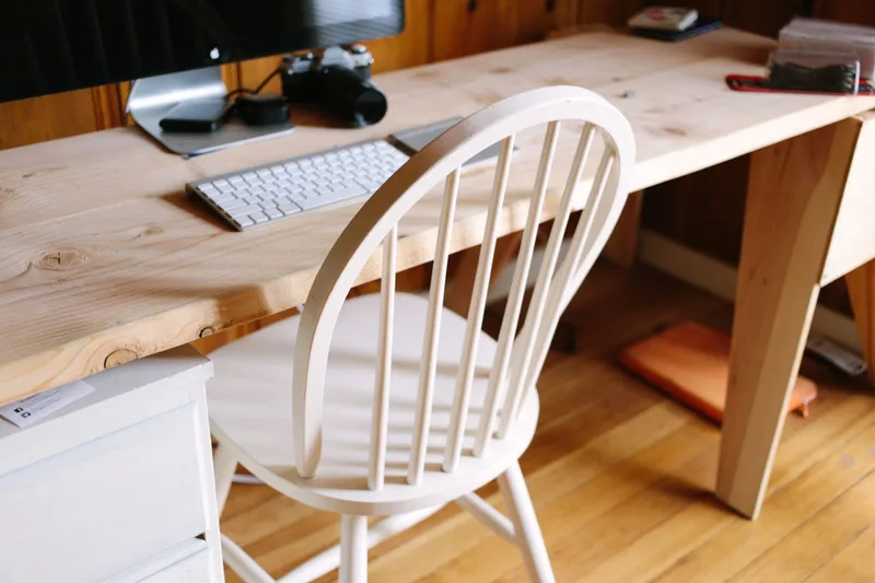 Minimalistic home office workspace with a laptop, coffee, and books on a white desk β a typical VA setup